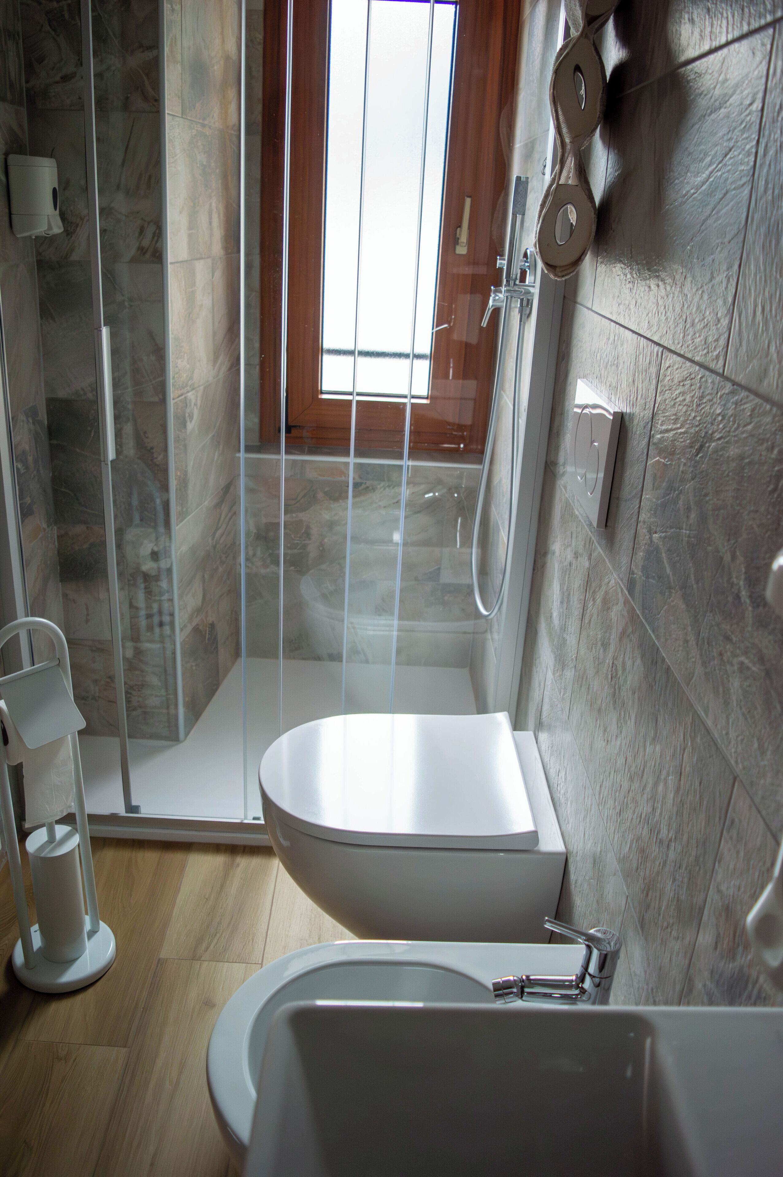 A modern bathroom with a glass-enclosed shower, a freestanding toilet, and a bathtub.