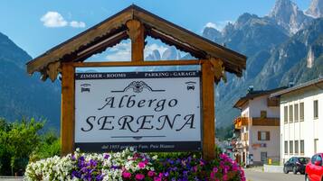 A sign for Albergo Serena with amenities listed, including rooms, parking, and a garage.