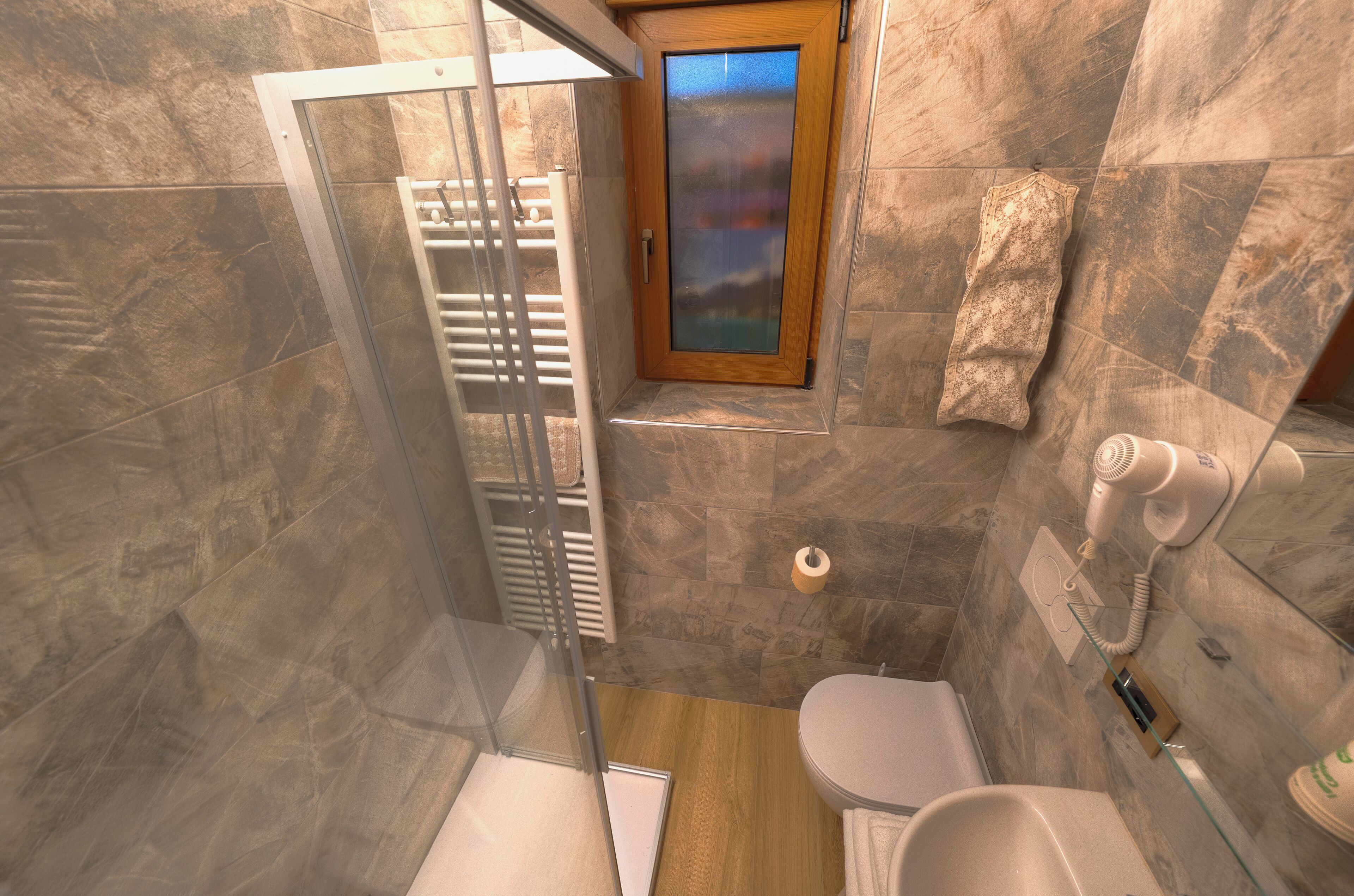 A bathroom with a shower, toilet, and a hairdryer on the wall.
