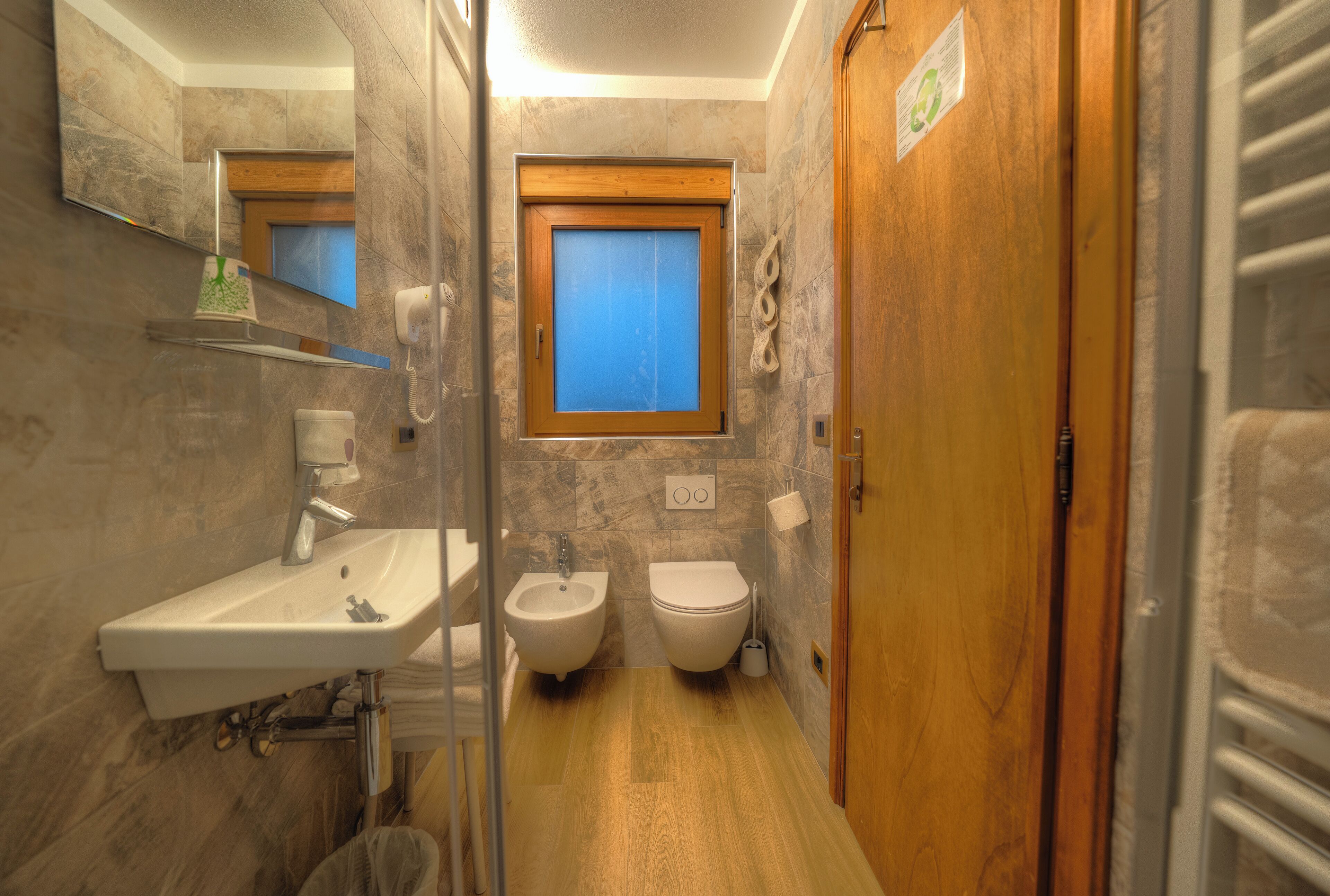 Un bagno con lavandino, bidet, water e porta in legno.