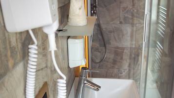 A bathroom with a white sink, a handheld hair dryer, and a shower.