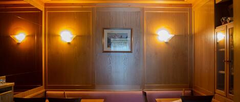 A cozy room with wooden paneling, a framed picture on the wall, and two tables with chairs.