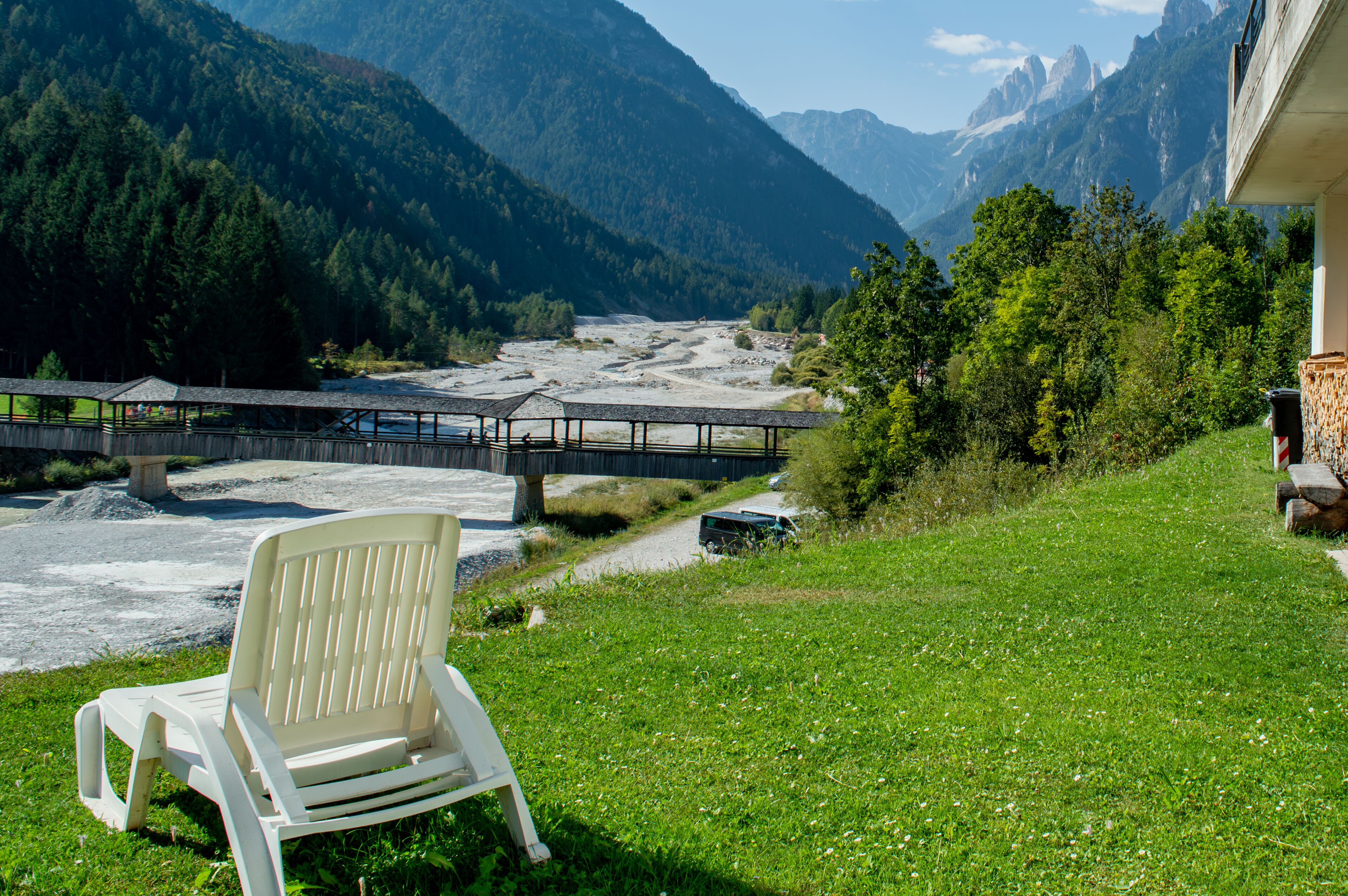 A chair on a grassy area with a view of a river and mountains.