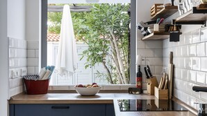 A modern kitchen with white tiles, a wooden countertop, and a window with a view of greenery. - Charming seaside house with home office (Pag)