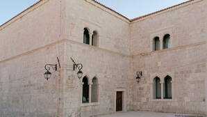 A historic building with arched windows and a central door, featuring stone walls and traditional lantern-style lighting. - Charming seaside house with home office (Pag)