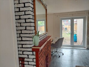 Relax in a clean, minimalist space with a brick accent wall, large mirror, and sliding glass door leading to an outdoor area.