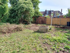 Surrounded by lush vegetation, this yard features a charming stone structure and a house with a tiled roof.