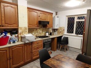 Kitchen area with stove, oven, sink, and dining table.