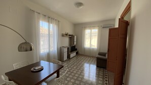 Une petite pièce bien éclairée, avec une table à manger, des chaises, un téléviseur et un sol à motifs.