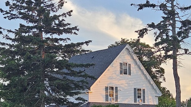 A two-story house with a porch and a covered front porch area. - Sunflower Guest Suites (Summerside)