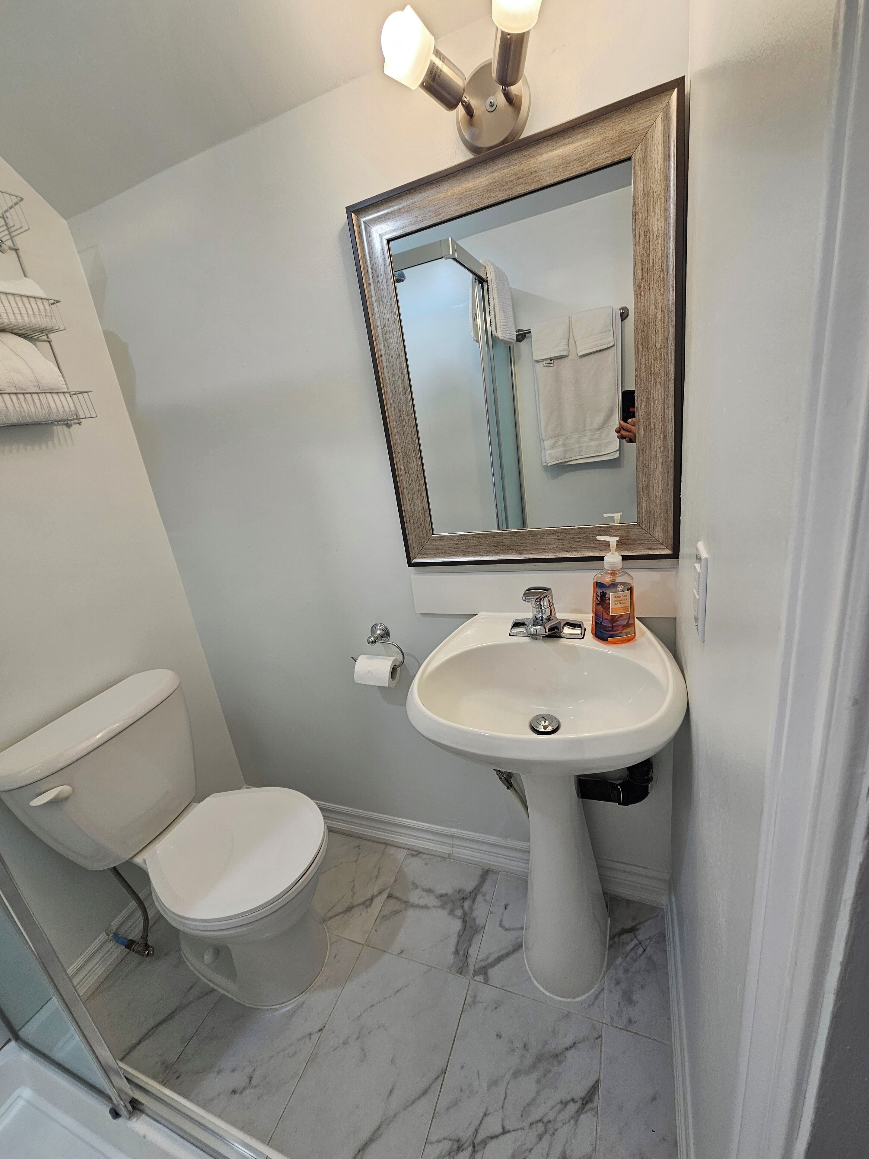 A bathroom with a toilet, sink, and mirror.