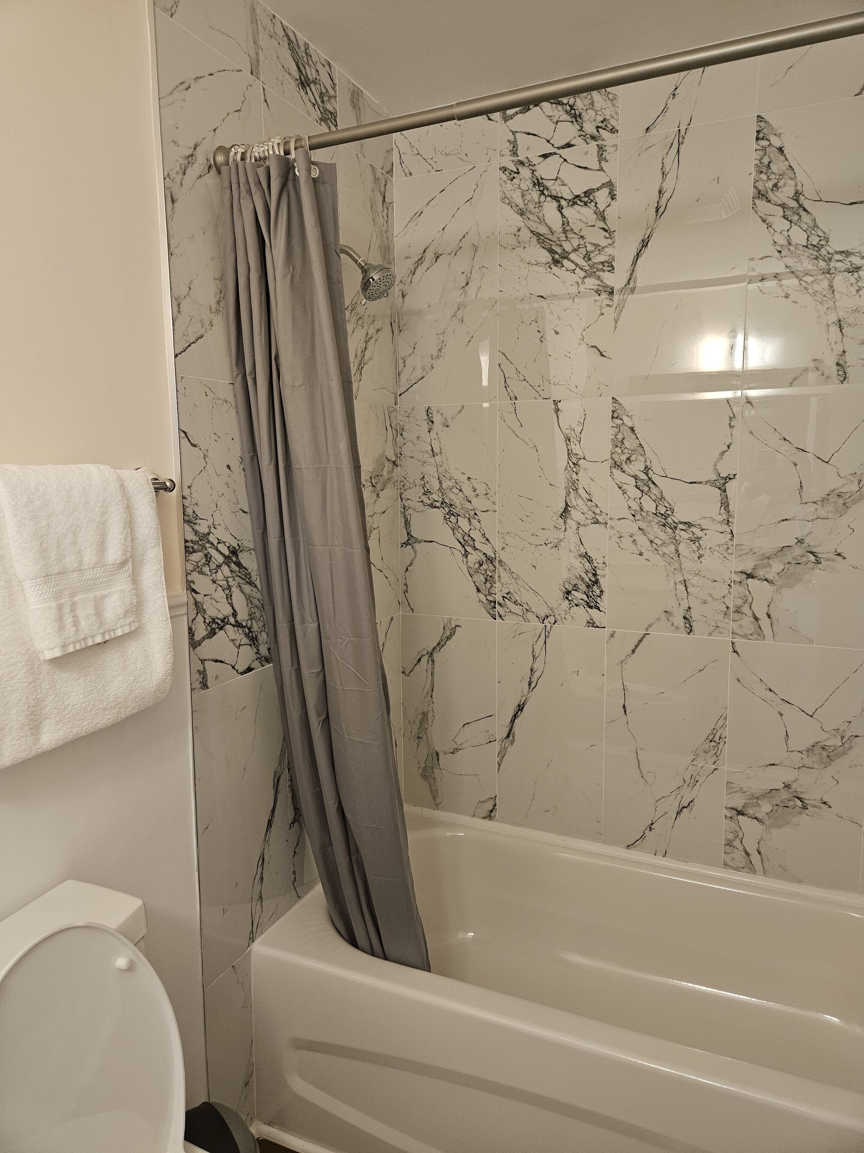 A bathroom with a bathtub, a shower curtain, and marble-patterned walls.