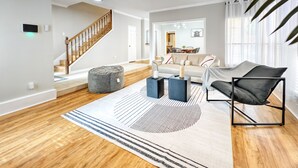 Ein modernes Wohnzimmer mit Holzboden, einem grauen Sitzsack, einer Couch, einem Couchtisch und einem Deckenventilator.
