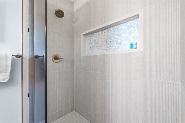 Une douche avec une fenêtre en verre dépoli, un porte-serviettes et un pommeau de douche.