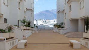 A courtyard with a brick pathway leading to a building with white walls and multiple windows. - Bright, Immaculate apartment in the Estepona port (Estepona)