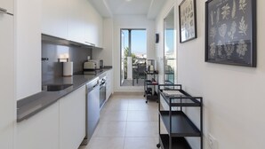 A modern kitchen with white cabinets, a grey countertop, and a black kitchen cart. - Bright, Immaculate apartment in the Estepona port (Estepona)