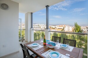 A balcony with a table set for dining, overlooking a cityscape. - Bright, Immaculate apartment in the Estepona port (Estepona)