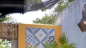 A potted palm tree in front of a wall with patterned tiles.