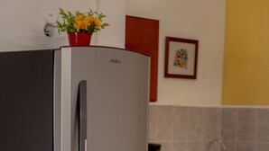 A stainless steel refrigerator with a water dispenser, red cabinets, and a tiled backsplash in a kitchen.
