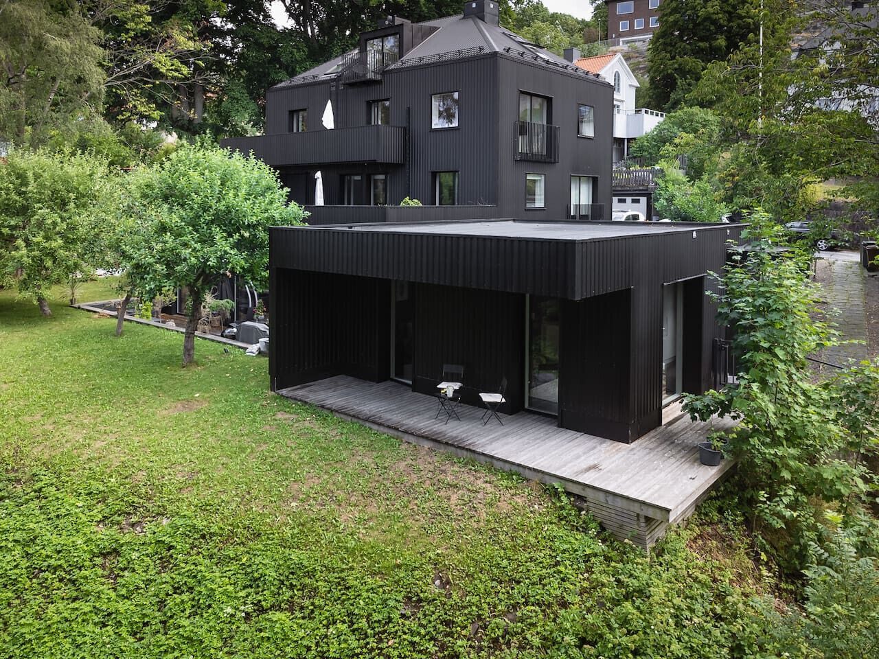 Une maison moderne à deux étages dotée d’un espace extérieur aménagé et abrité.