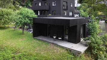 Une maison moderne à deux étages dotée d’un espace extérieur aménagé et abrité.