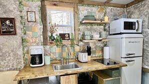 Et kompakt køkken med vask, kaffemaskine, mikroovn og køleskab.