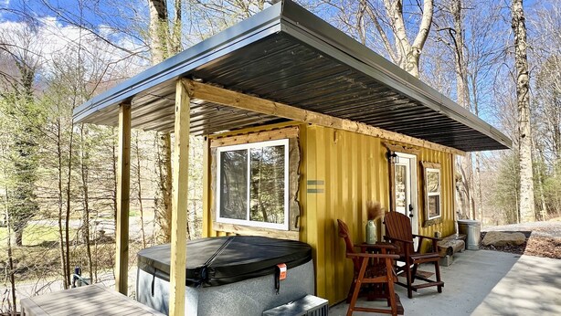 En hyggelig hytte med overdækket veranda, boblebad og terrasse med siddepladser.