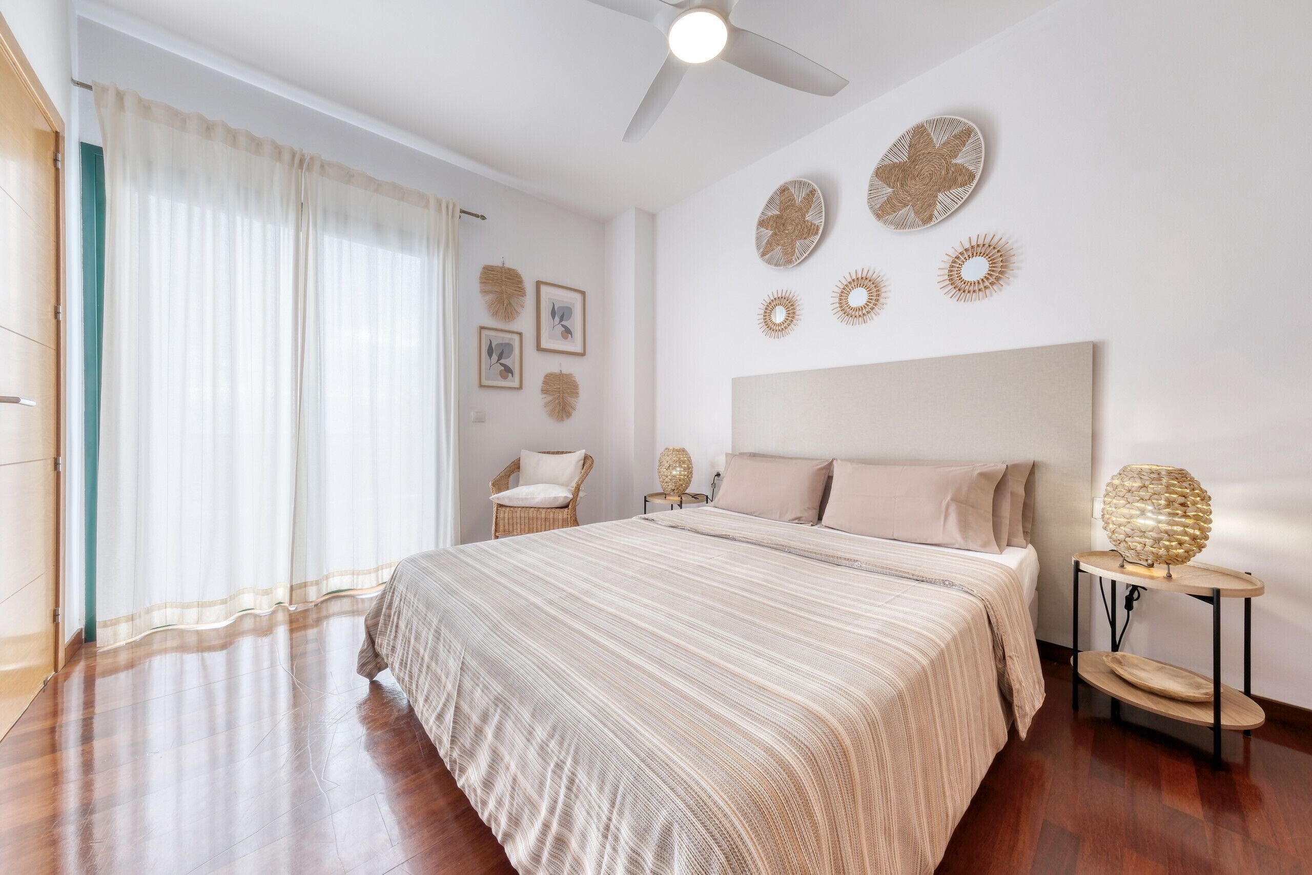 A bedroom with a large bed, a ceiling fan, and wall decor.