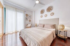 A bedroom with a large bed, a ceiling fan, and wall decor. - Costa Esmeralda - Sun and Relax By LVH (Costa Teguise)