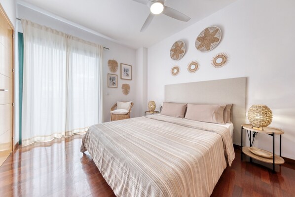 Une chambre avec un grand lit, un ventilateur de plafond et des éléments de décoration murale.
