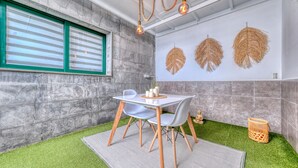 Une pièce moderne avec un mur en pierre, une fenêtre avec des stores, une table avec des chaises et des éléments décoratifs fixés au mur.