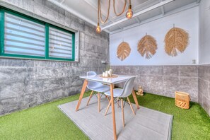 A modern room with a stone wall, a window with blinds, a table with chairs, and decorative wall hangings.
