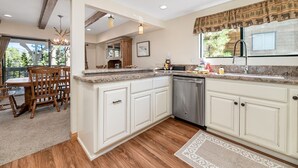 A modern kitchen with white cabinetry, granite countertops, and a built-in dishwasher. - Whiskey Pines Chalet (Big Bear Lake)