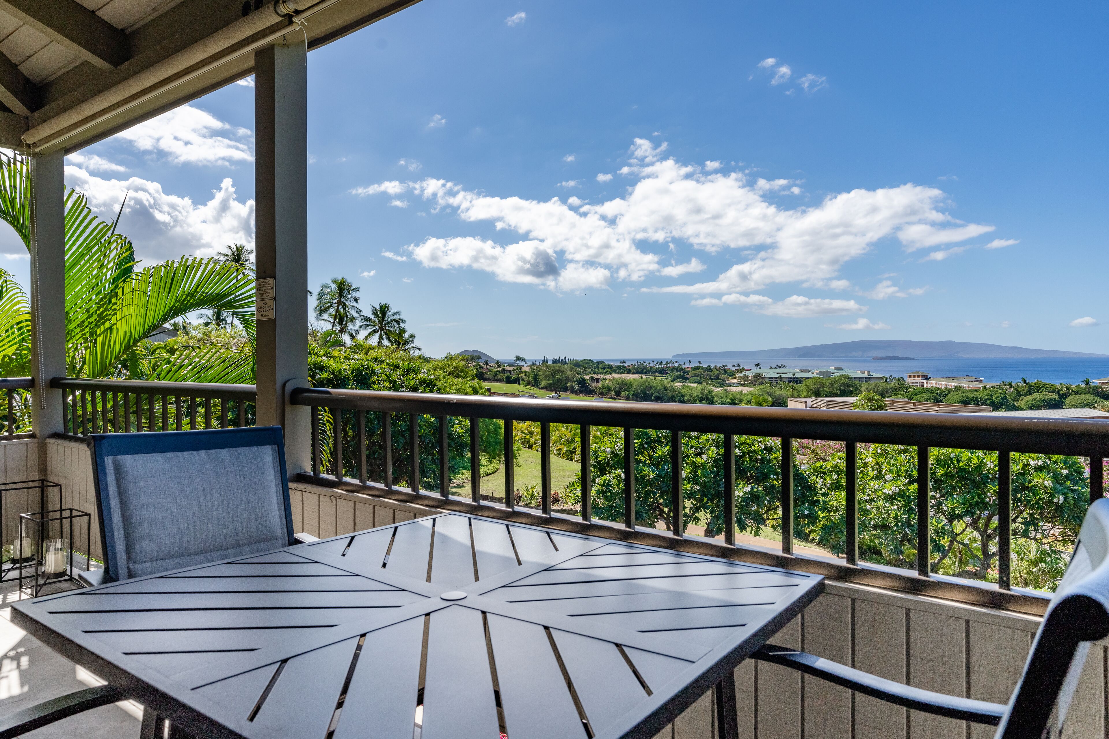 Ein Balkon mit Tisch und Stühlen, der einen schönen Blick auf die Küste und sanfte Hügel bietet.