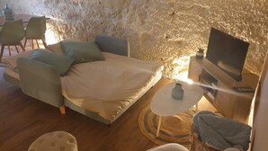 Ein gemütliches Zimmer mit Bett, Fernseher und einer Sitzecke mit Stühlen und einem kleinen Tisch.