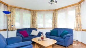 A living room with two blue sofas, a wooden coffee table, and a floor lamp. - Amaryllis by Interhome (Saas-Grund)