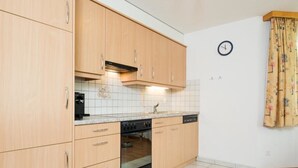 A kitchen with wooden cabinets, a tiled backsplash, a stove, and a dishwasher. - Amaryllis by Interhome (Saas-Grund)