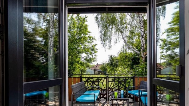 Un espacio al aire libre moderno con sillas azules y una valla de metal negro.