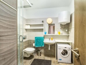 Un baño pequeño con inodoro, lavamanos y lavadora.