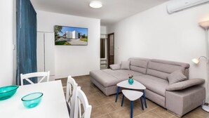 Una sala de estar moderna con un sofá gris, una mesita blanca y un jarrón azul aguamarina.