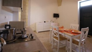 A modern kitchen with white cabinetry, a dining area with white chairs and a table set for two, and a stone arch ceiling. - Spicchi di Salento - Arancio by Interhome (Vernole)