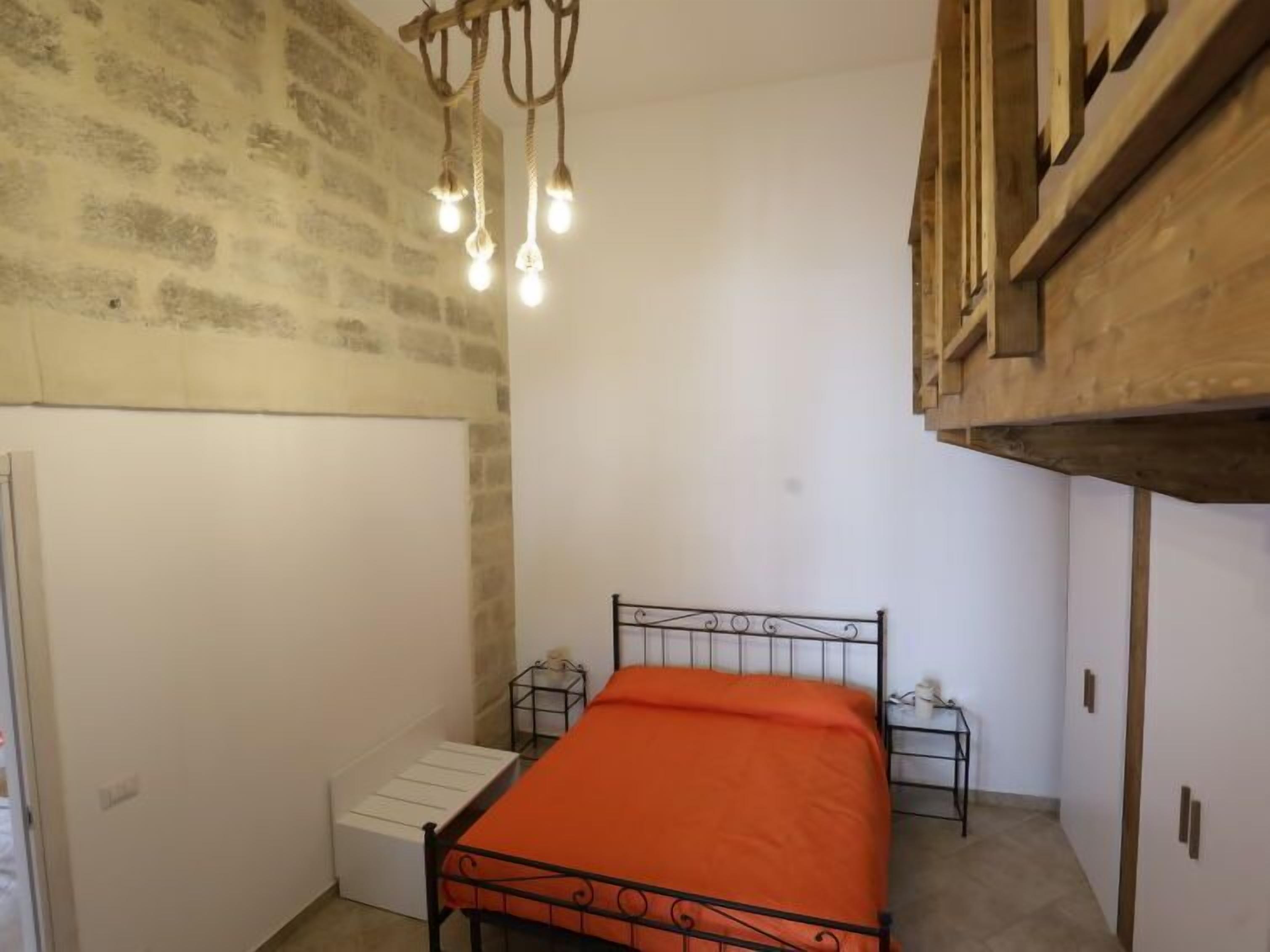 A small, narrow room with a single bed, a white radiator, and a wooden ceiling.