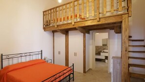 A bedroom with a bed, a wooden staircase, and a bathroom visible through an open door. - Spicchi di Salento - Arancio by Interhome (Vernole)