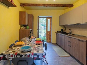 Un comedor con mesa lista para cuatro, una cocina con armarios de madera y vistas a través de un ventanal.