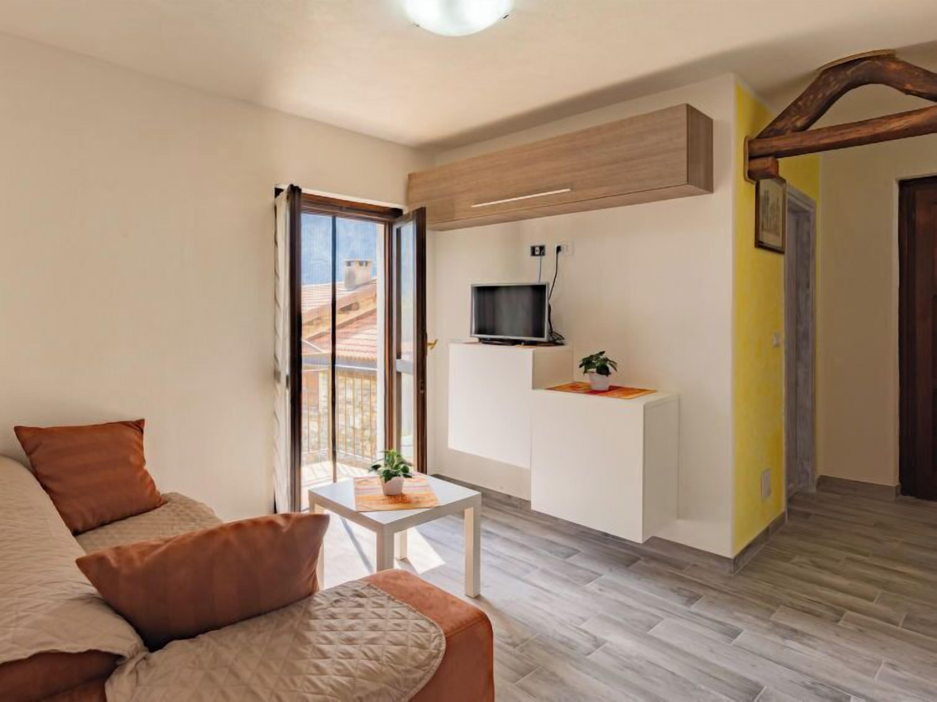 Un salon moderne avec un canapé, une petite table, un téléviseur et une fenêtre donnant sur des immeubles.