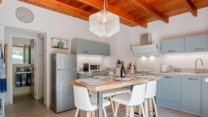Una cocina moderna con techo de madera, armarios azul claro y un refrigerador de acero inoxidable, además de una zona de bar con taburetes blancos.