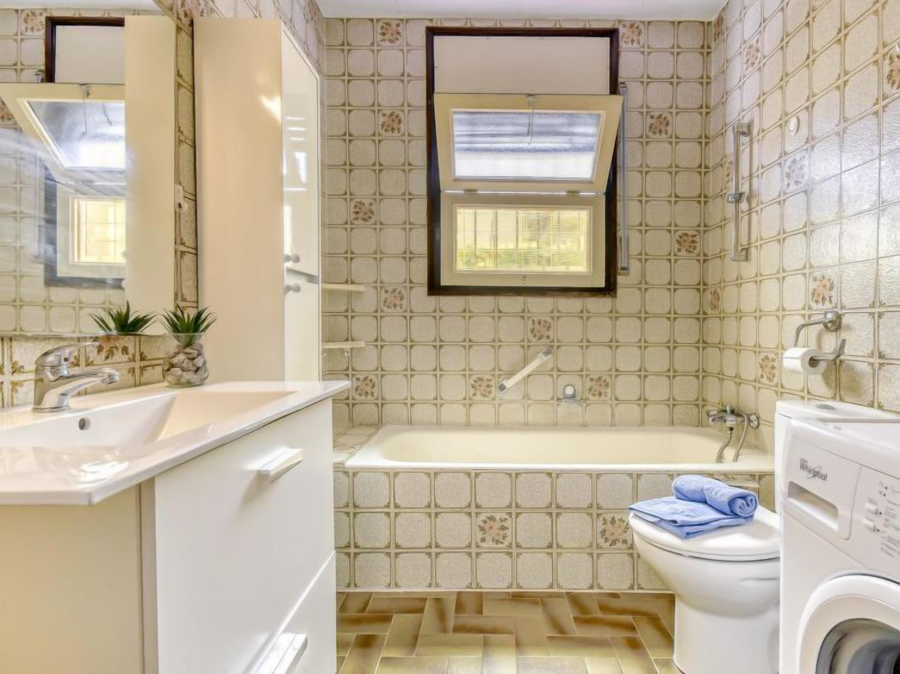 A bathroom with a bathtub, toilet, and washing machine.