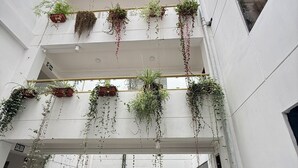 A multi-level atrium with hanging planters and a central staircase. - Hotel Inkasabios Cusco (Cusco)