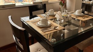 A dining table set for four with a view of mountains through the window. - Hotel Inkasabios Cusco (Cusco)