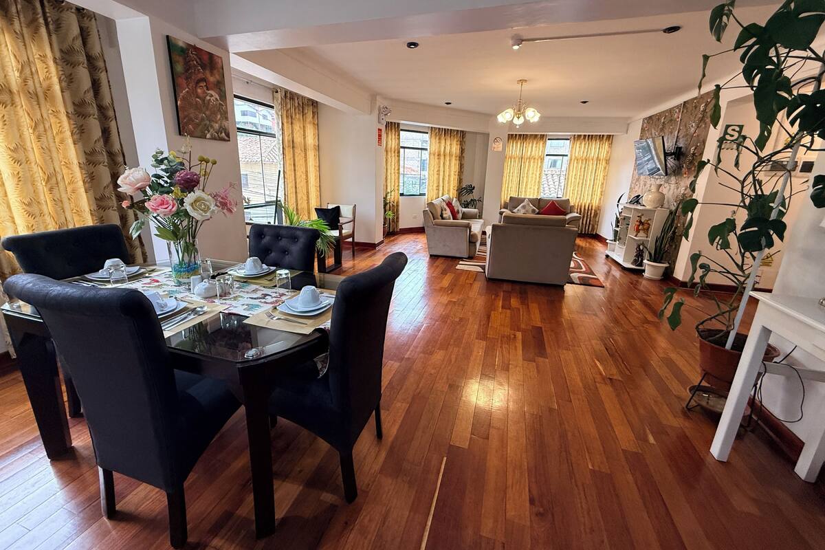 A spacious living area with a dining table set for four, a sofa, and a coffee table.